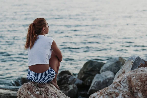 坐在岩石上望着大海的女人 — 图库照片
