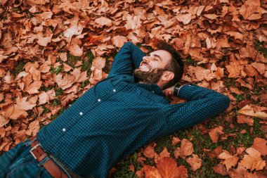 Genç adam yerde yatan sonbahar yaprakları kaplı