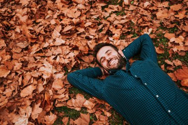 Genç adam yerde yatan sonbahar yaprakları kaplı