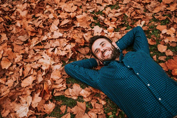 stock image Young man lying down on the ground covered in autumn leaves