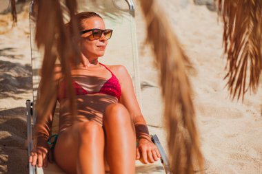 Plajda palmiye ağacı altında yatan genç kadın bırakır