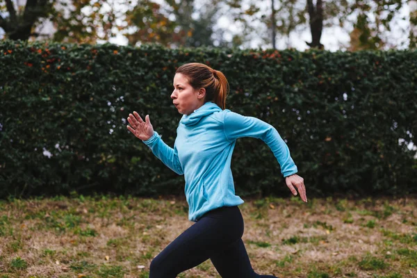 Woman running. Female runner jogging, training for marathon. Fit girl fitness athlete model exercising outdoor.