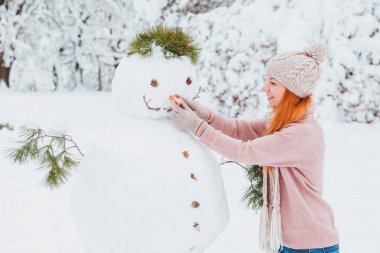 Genç kadın parkta kardan adam yapma