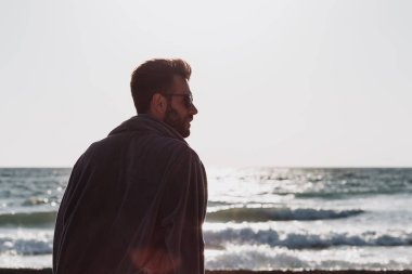 Sunset plajında bornozlu genç adam