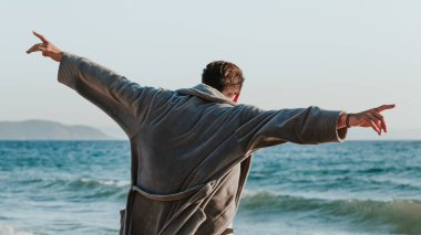 Sunset plajında bornozlu genç adam