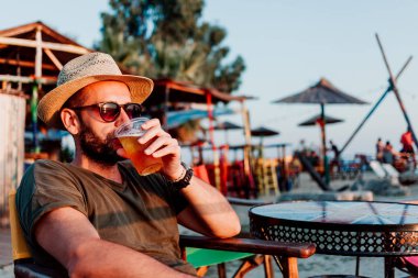 Genç adam bir plaj barda bira keyfi