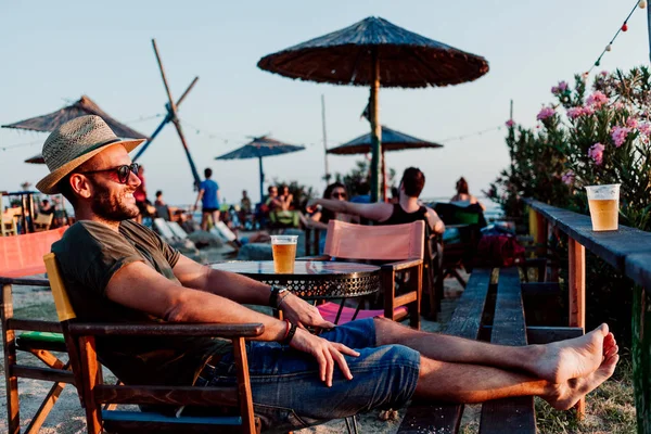 Genç adam bir plaj barda bira keyfi