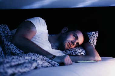 Geceleri yatakta Smartphone kullanan genç adam