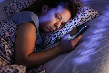 Geceleri yatakta Smartphone kullanan genç kadın