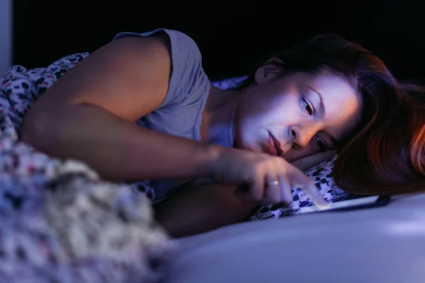 晚上在床上使用智能手机的年轻女子 — 图库照片