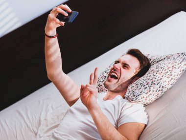 Young man taking a selfie in the bed
