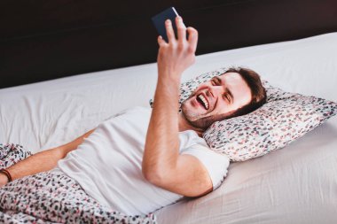 Young man taking a selfie in the bed