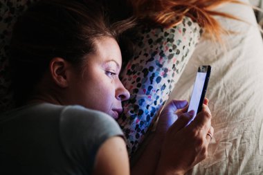 Geceleri yatakta Smartphone kullanan genç kadın