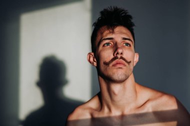 Genç gömleksiz adam bıyık düşünce ile