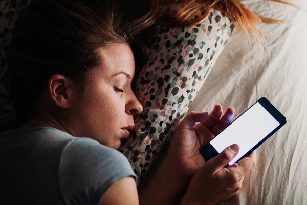 Young woman using smartphone in bed at night