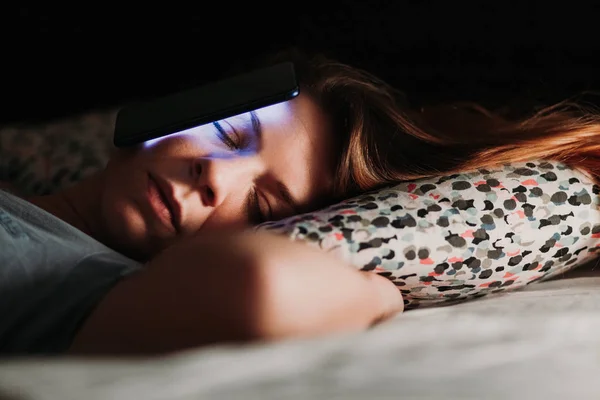 Young woman using smartphone in bed at night