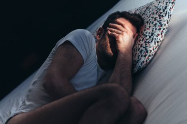 Genç adam yatakta acı içinde depresif