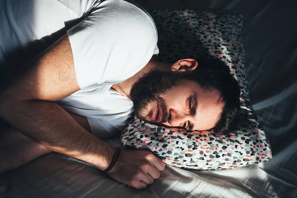 Young depressed man crying in bed