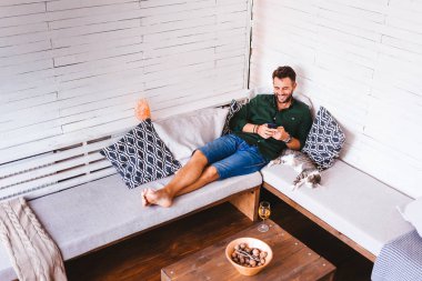 Oturma odasında Smartphone kullanan genç adam