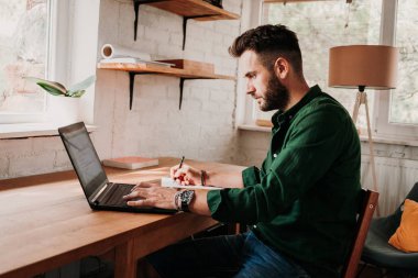 Bir dizüstü bilgisayarda çalışan genç casual adam