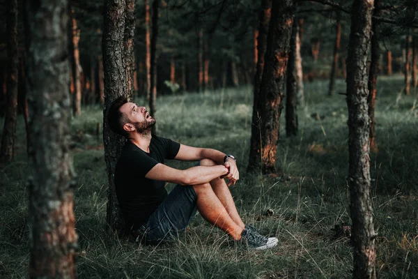 Young depressed man sitting alone in the forest