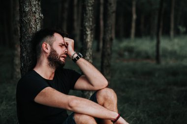 Ormanda tek başına oturan genç depresif adam