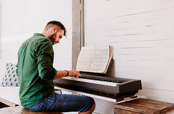 Young man playing electric piano at home