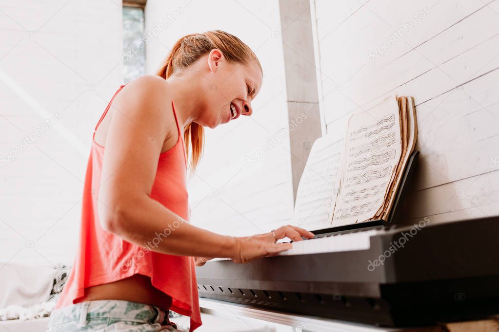 Young woman enjoying playing electric piano at home
