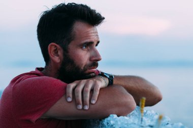 Ufka bakarak denizin kenarında genç üzgün adam