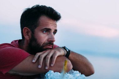 Ufka bakarak denizin kenarında genç üzgün adam