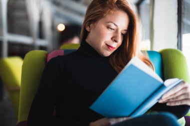 Bir kitap okuma bir kafede oturan genç kadın