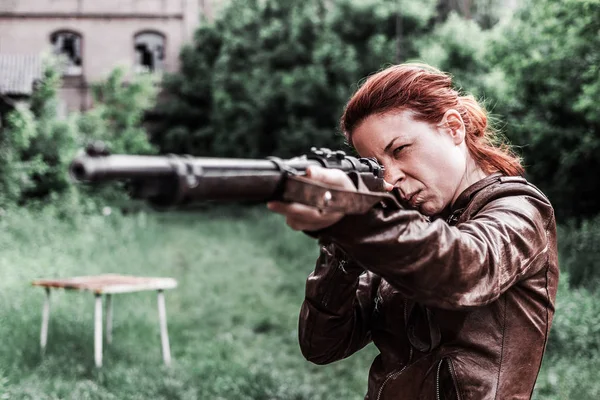 Eski bir tüfek tutan genç kadın