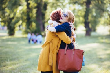 Olgun anne ve yetişkin kızı parkta sarılma