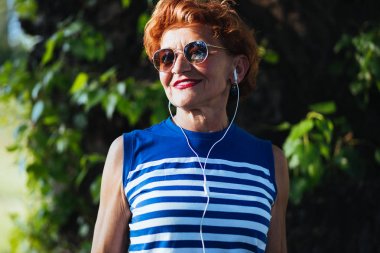 Parkta kulaklıkla müzik dinleyen olgun kadın