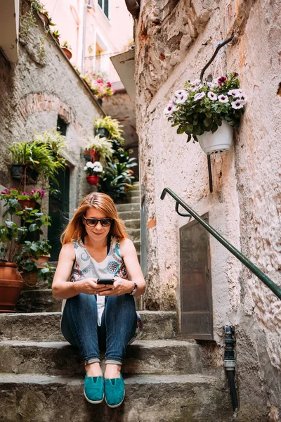 Young Woman Using Smartphone Sitting Steps Italian Village Stock Photo