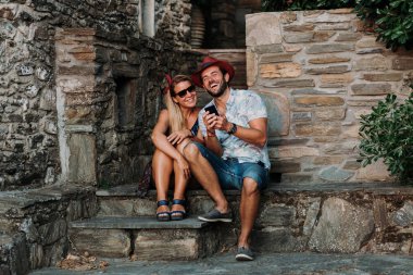 Yunanistan 'da eski bir kasabanın merdivenlerinde akıllı telefon kullanan genç bir çift