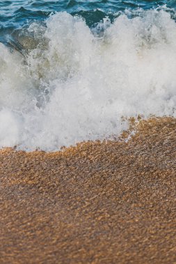 Sıcak gün batımında sahile vuran bir dalganın yakın çekimi