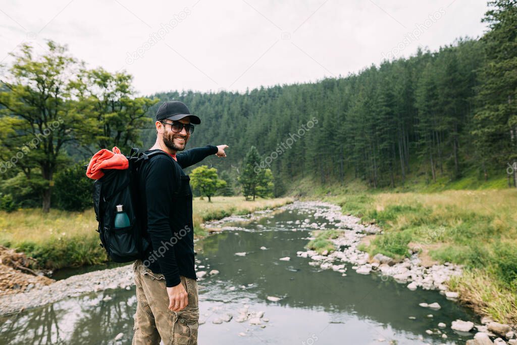 Young male nature explorer enjoying the view of the river in wilderness