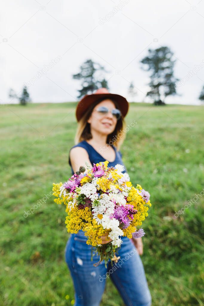 Young woman holding flower bouquet  in the field