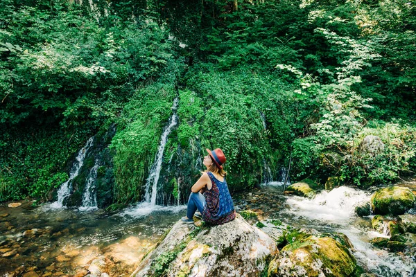 Young female nature explorer enjoying by the waterfalls