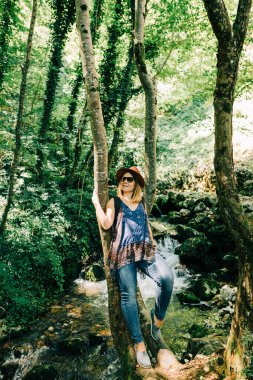 Ormandaki ağacın yanında genç bir kadın.