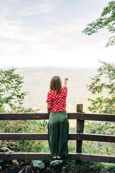 Young female nature explorer enjoying the view from mountain viewpoint