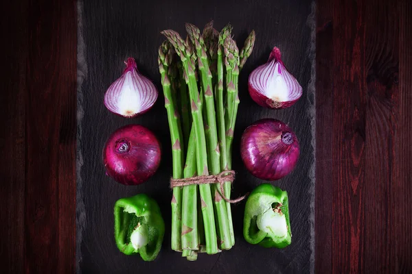 Bir demet taze kuşkonmaz soğanlı, soğanlı, yeşil biberli ve ahşap kaplamalı. Düz yatıyordu. Alçak tuş.