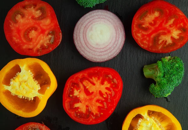 Ragoo concept with resh ripe tomatoes, peppers, brokkoli, onion close-up on black shale board. Flat lay. Low key.