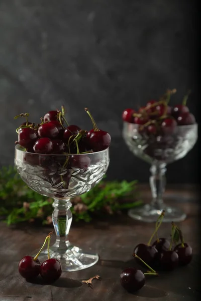 Two crystal dessert bowls filled with ripe cold cherries. Low key.