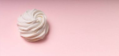 Pembe arka plana karşı beyaz bir şekerleme. Yumuşak ışık. Boşluğu kopyala.