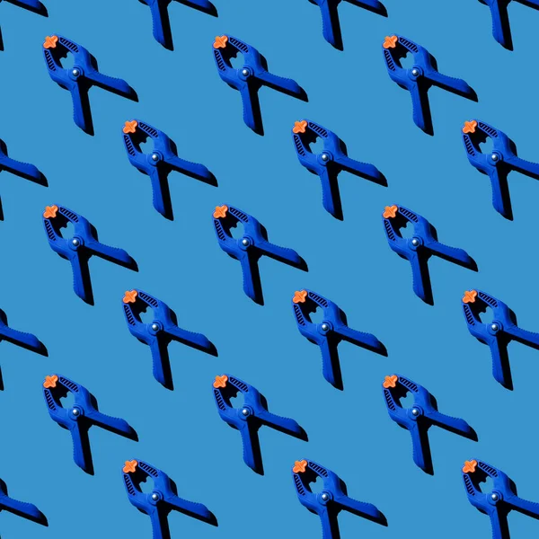 Turuncu kabzalı mavi çok amaçlı kıskaçların kusursuz deseni. Çapraz oryantasyon. Mavi arkaplan.