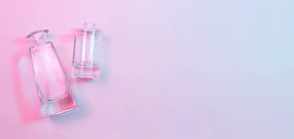 Bir silindirik yuvarlak taban ve bir şekillendirilmiş kare kare kristal berrak boş cam şişeler mavi ve pembe neon ışıklarda renkli arka planda yatıyor..