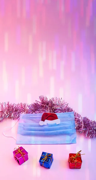 Coronavirus Noel ve tıbbi maskeli yeni yıl konsepti, Noel Baba 'nın şapkası, Noel süsü, neon ışıklı hediye kutuları. Boşluğu kopyala.