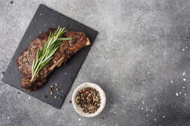 Hazır - masada kemiğin üzerinde biftek, bıçak, üst görüş, koyu arka plan, biber ve tuz, biberiye